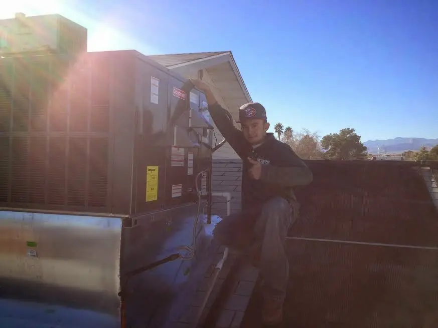 HVAC technician performing Air Duct Cleaning on a rooftop unit in Macomb