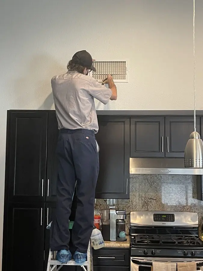 Technician inspecting an air vent during HVAC service in Macomb